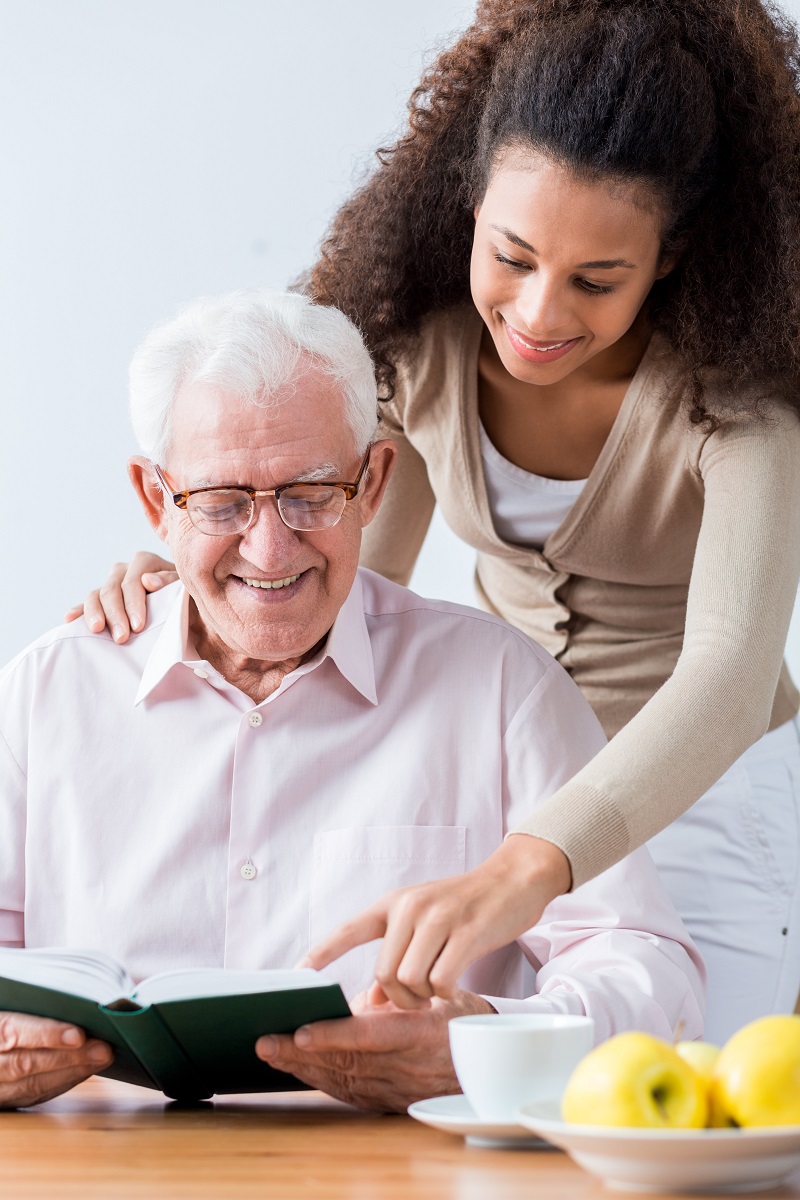 Compassionate caregiver reading with elderly resident in comfortable home setting